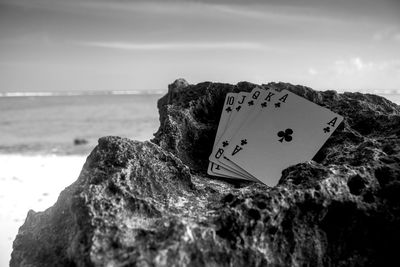 Close-up of heart shape on rock at beach against sky