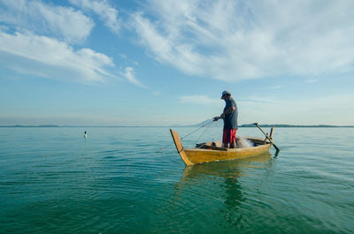 Man fishing in sea against sky