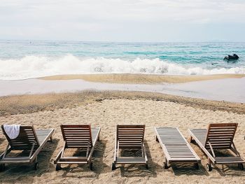 Empty lounge chairs on shore at beach
