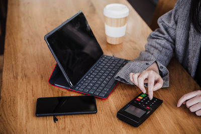 Midsection of woman using laptop at table