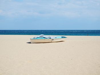 Deck chairs on beach against sky