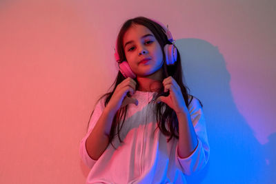 Little girl in headphones dancing to music in neon light