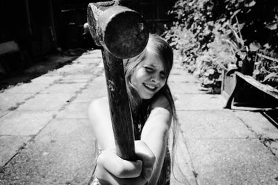 Girl holding hammer on footpath