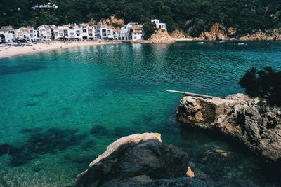 Rocks by sea against buildings in city