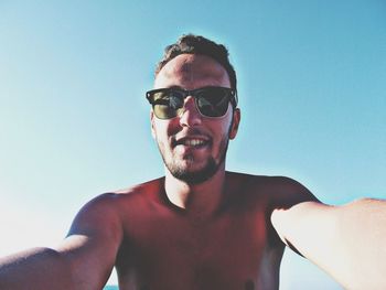 View of young man wearing sunglasses against blue sky