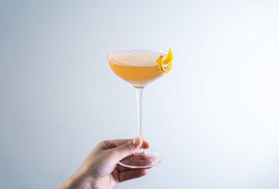 Holding a glass of golden cocktail on a white background