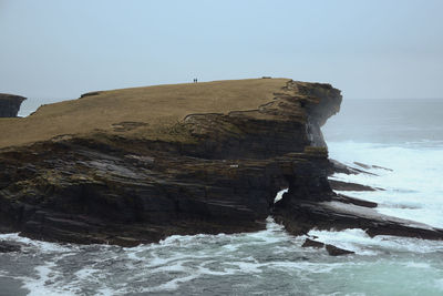 Rock formation in sea against clear sky