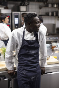 Happy man looking away while standing in commercial kitchen