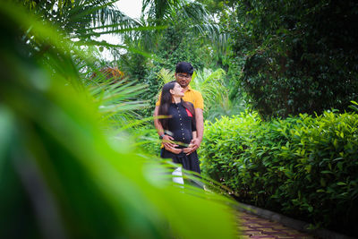 Young man with pregnant woman amidst plants