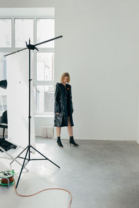 Rear view of woman standing against wall at home