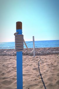 Wooden posts on beach against clear sky