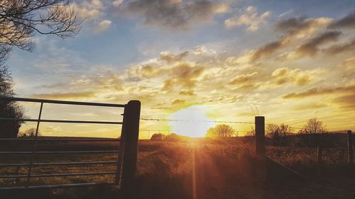 Silhouette field against sky during sunset