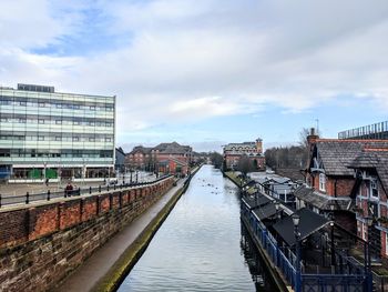 Bridge over river amidst buildings in city against sky