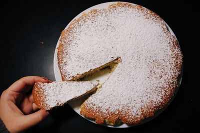 Close-up of hand holding ice cream against black background