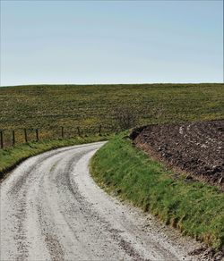 Dirt road passing through field