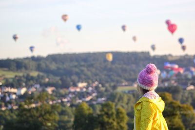 Rear view of woman with hot air balloon against sky