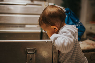 Cute baby girl looking in drawer at home