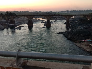 Bridge over river against sky during sunset