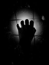 Silhouette person hand against black background