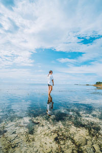 Full length of woman standing in sea against sky