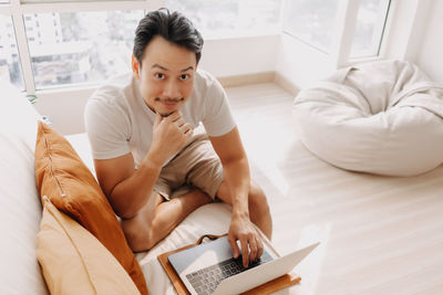 Portrait of smiling man using laptop at home