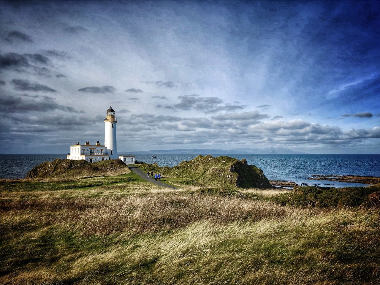 LIGHTHOUSE BY SEA AND BUILDINGS AGAINST SKY