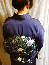 Rear view of woman standing by purple flower