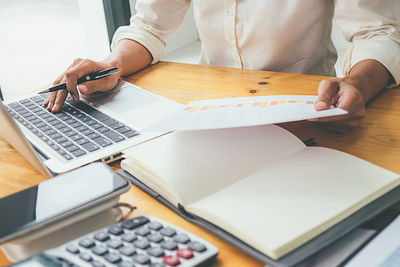 Midsection of man using laptop on table