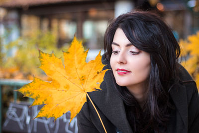 Close-up portrait of woman with autumn leaves