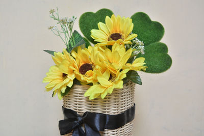 Close-up of yellow flower in vase against wall