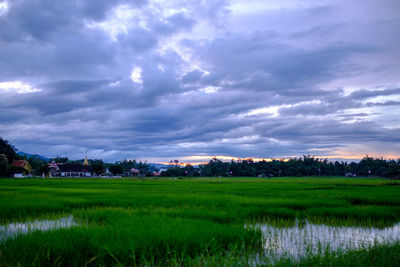 Scenic view of field against cloudy sky