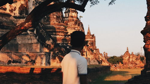 Rear view of young man standing outside temple