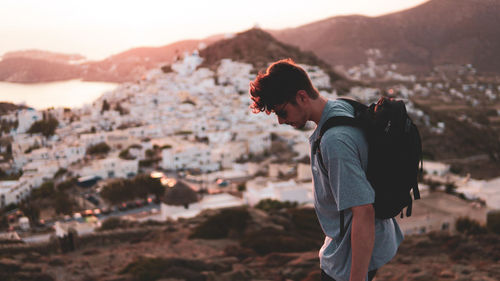 Side view of young man standing on mountain during sunset