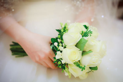 Midsection of bride holding bouquet