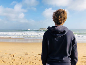 Rear view of man looking at sea against sky