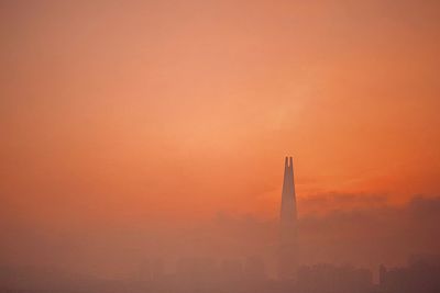 Silhouette built structure against orange sky