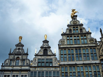 Low angle view of buildings in town against cloudy sky