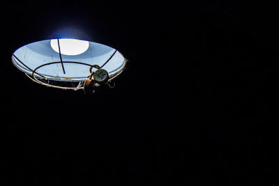 Padlocks on illuminated pendant light against black background