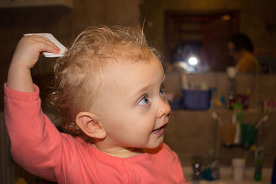 Cute baby girl combing hair at home