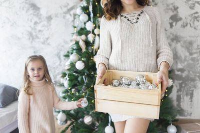 Mother and daughter standing by christmas tree