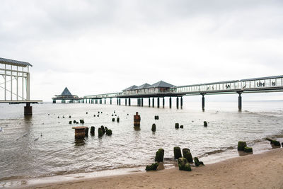 View of wooden posts on beach against cloudy sky