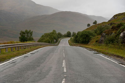 Empty road amidst mountains against sky