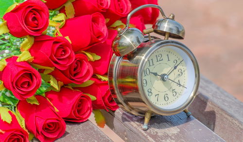 Alarm clock with artificial roses on table