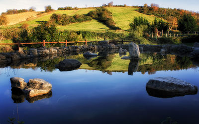 Rocks by lake against sky