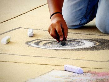 Midsection of person drawing with chalk on cardboard