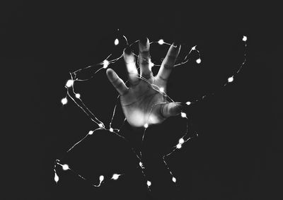 Midsection of person holding illuminated lighting equipment against black background