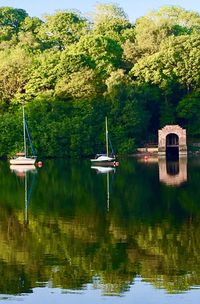 Boat moored on lake by trees against sky