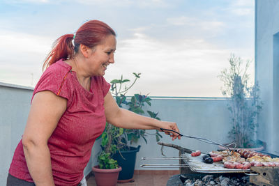 Woman preparing food on barbeque grill in balcony