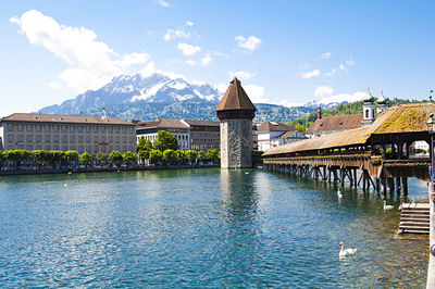 Bridge over river by buildings against sky