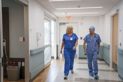 Surgeon and nurse talking while walking in hospital corridor